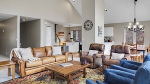 A spacious living room with leather sofas, a wooden coffee table, and a patterned rug. - Secluded Creekside Home | Incredible Views | A/C | Private Deck | STR2025-036 (Ridgway)