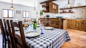 Un coin repas avec une nappe à carreaux, des chaises en bois et une bouteille de vin.