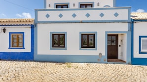 Un bâtiment à deux étages, doté d’un toit en tuiles, d’une cheminée et d’un sol pavé.