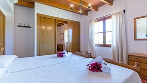 Habitación de hotel con una cama grande, cabecero de madera, candelabro, ventana con cortinas y un armario de madera.