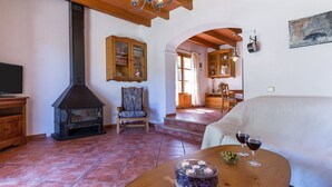 Una sala de estar acogedora con chimenea, un mueble de madera, una silla y una mesa con vasos y velas.