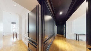 A hallway with wooden flooring, white walls, and dark wooden doors.