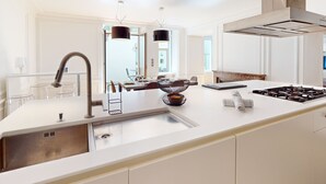 A modern kitchen with a large island, stainless steel appliances, and pendant lighting.
