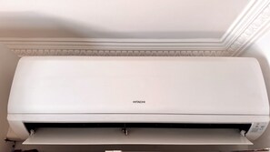 Eine Hitachi-Klimaanlage ist an einer Wand montiert, oberhalb davon befindet sich ein dekorativer Stuckrahmen.