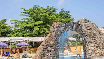 Una piscina al aire libre, sombrillas, sillones reclinables de piscina