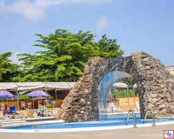 Una piscina al aire libre, sombrillas, sillones reclinables de piscina