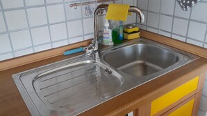 A kitchen with a stainless steel sink, a wooden countertop, and a yellow cabinet. - 2 room vacation apartment Strandpromenade Sankt Peter Ording (Sankt Peter-Ording)