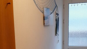 A room with a wooden dresser, a hammock, and a large window with a view. - 2 room vacation apartment Strandpromenade Sankt Peter Ording (Sankt Peter-Ording)