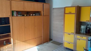 A compact kitchen with wooden cabinets, a microwave, and a coffee maker. - 2 room vacation apartment Strandpromenade Sankt Peter Ording (Sankt Peter-Ording)