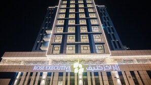 Un edificio de hotel con señalización iluminada que dice "ROSE EXECUTIVE Hotel".