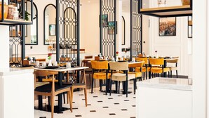 Un restaurante moderno con sillas amarillas, decoración blanco y negro, y piso de baldosas.