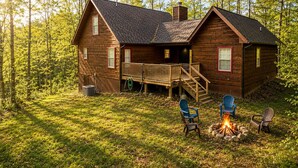 Eine Hütte mit Terrasse, Feuerstelle und Sitzgelegenheiten im Freien.