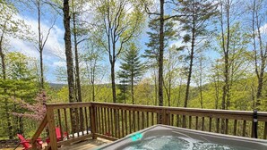 Ein Whirlpool auf einer Holzterrasse mit Blick auf einen Wald.