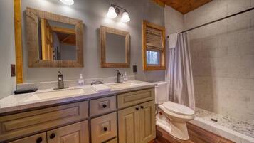 Une salle de bain avec un meuble-lavabo en bois, deux vasques, des toilettes et une douche avec un rideau.