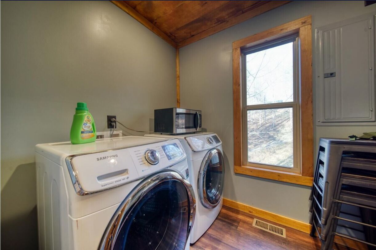 Une buanderie équipée d’un lave-linge, d’un sèche-linge et d’un four à micro-ondes posé sur le dessus.