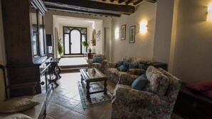 Un salon avec un canapé, une table basse et une cheminée. Un escalier mène à l’étage supérieur.