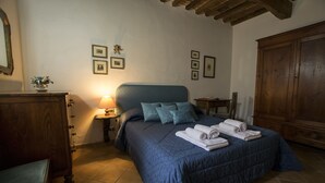 Une chambre à coucher avec un lit, une commode, une chaise et une lampe.