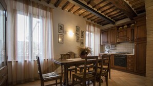 Une cuisine avec des meubles de rangement en bois, une table à manger avec des chaises et un sol carrelé.