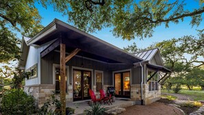 A modern house with a covered porch, stone foundation, and a well-maintained garden.