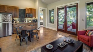 A spacious kitchen with wooden cabinets, a stainless steel refrigerator, and a dining area with a wooden table and chairs.
