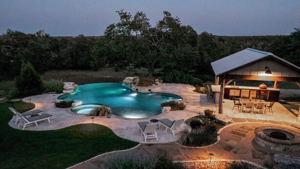 A backyard with a swimming pool, outdoor seating, and a barbecue area.
