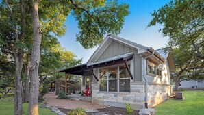 A modern house with a stone facade, large windows, and a covered porch.