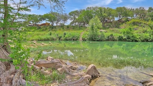Paisaje natural con un estanque, árboles y un puente de madera.