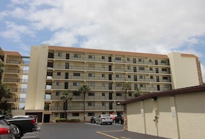 A multi-story hotel with a parking lot in front.