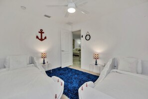 A hotel room with two beds, a ceiling fan, and a blue carpet.