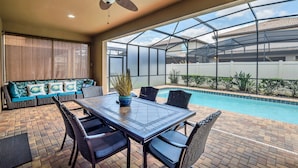 A covered patio with a pool, a dining table, and seating. - Pool * Movie Theater * near Free Waterpark (Kissimmee)