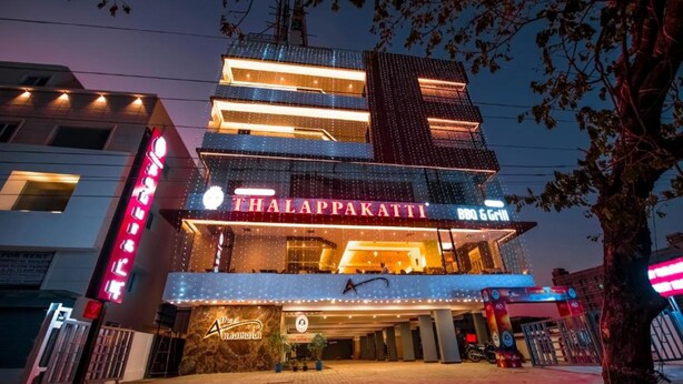 A multi-story building with a prominent sign for 'Thalappakatti B&B & Grill'. - Hotel Annamalai (Bahur)