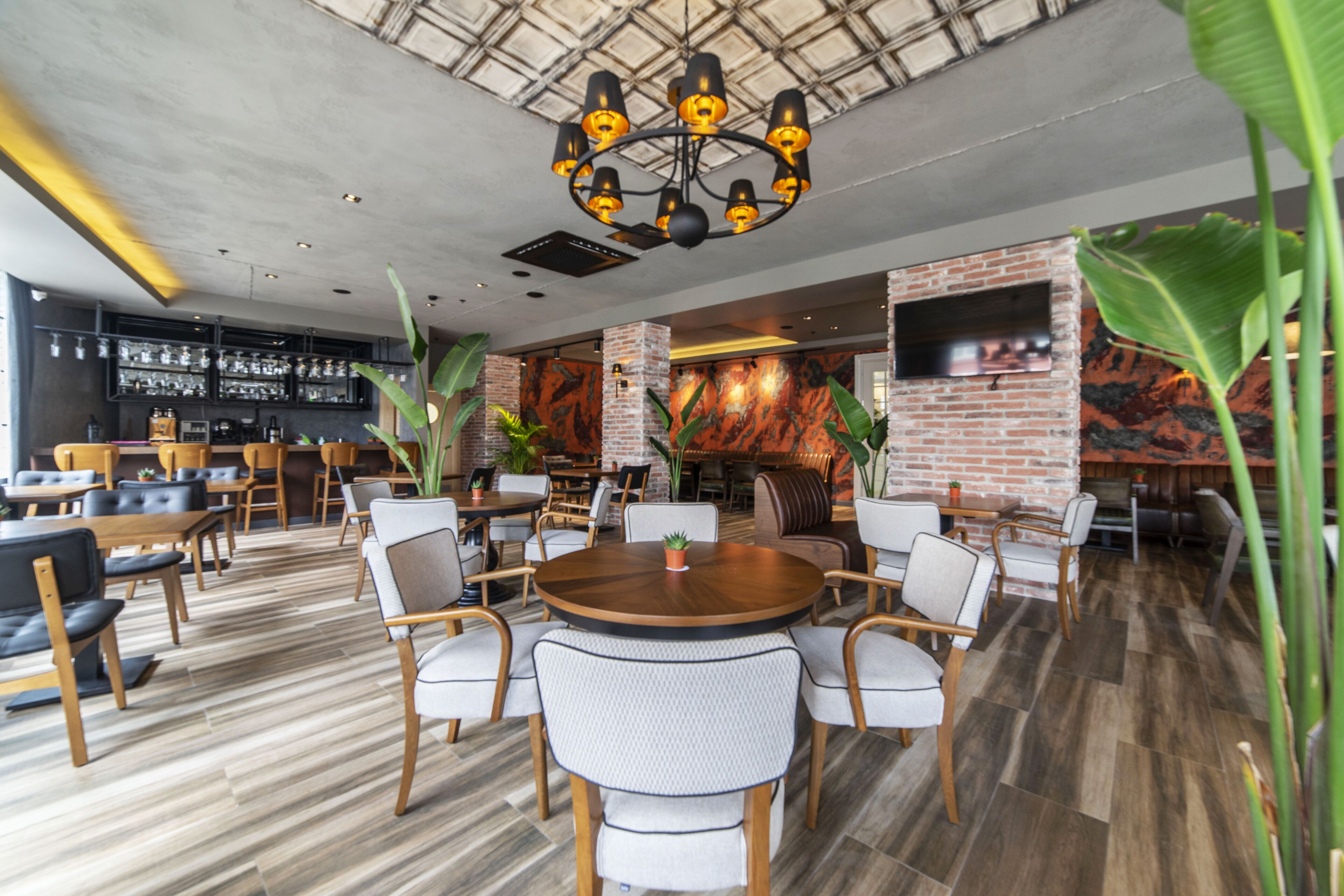 A modern restaurant with a brick wall, wooden tables, and chairs.