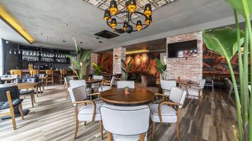A modern restaurant with a brick wall, wooden tables, and chairs.