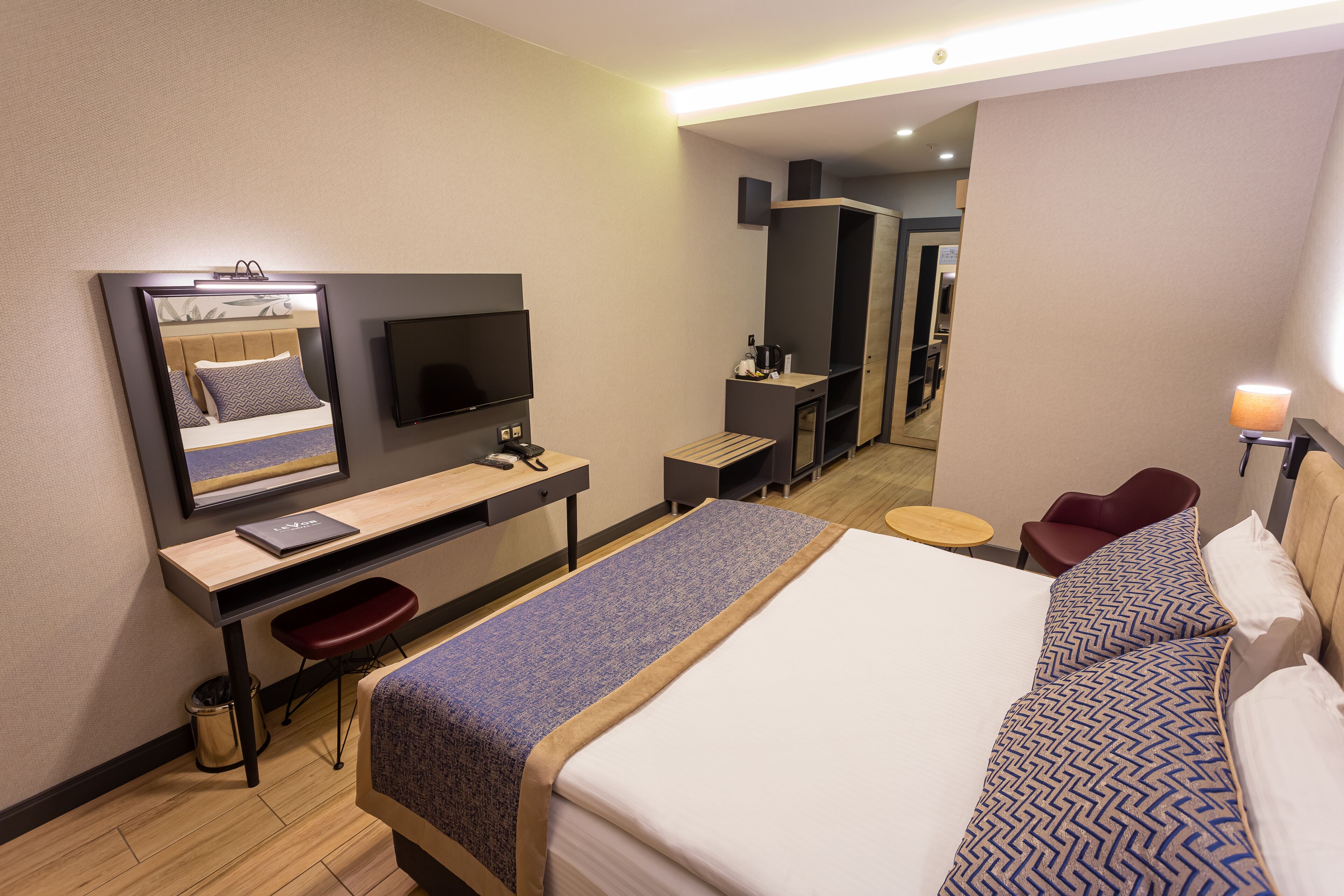 Une chambre d’hôtel avec un lit, un bureau, une chaise, une télévision et une petite table.