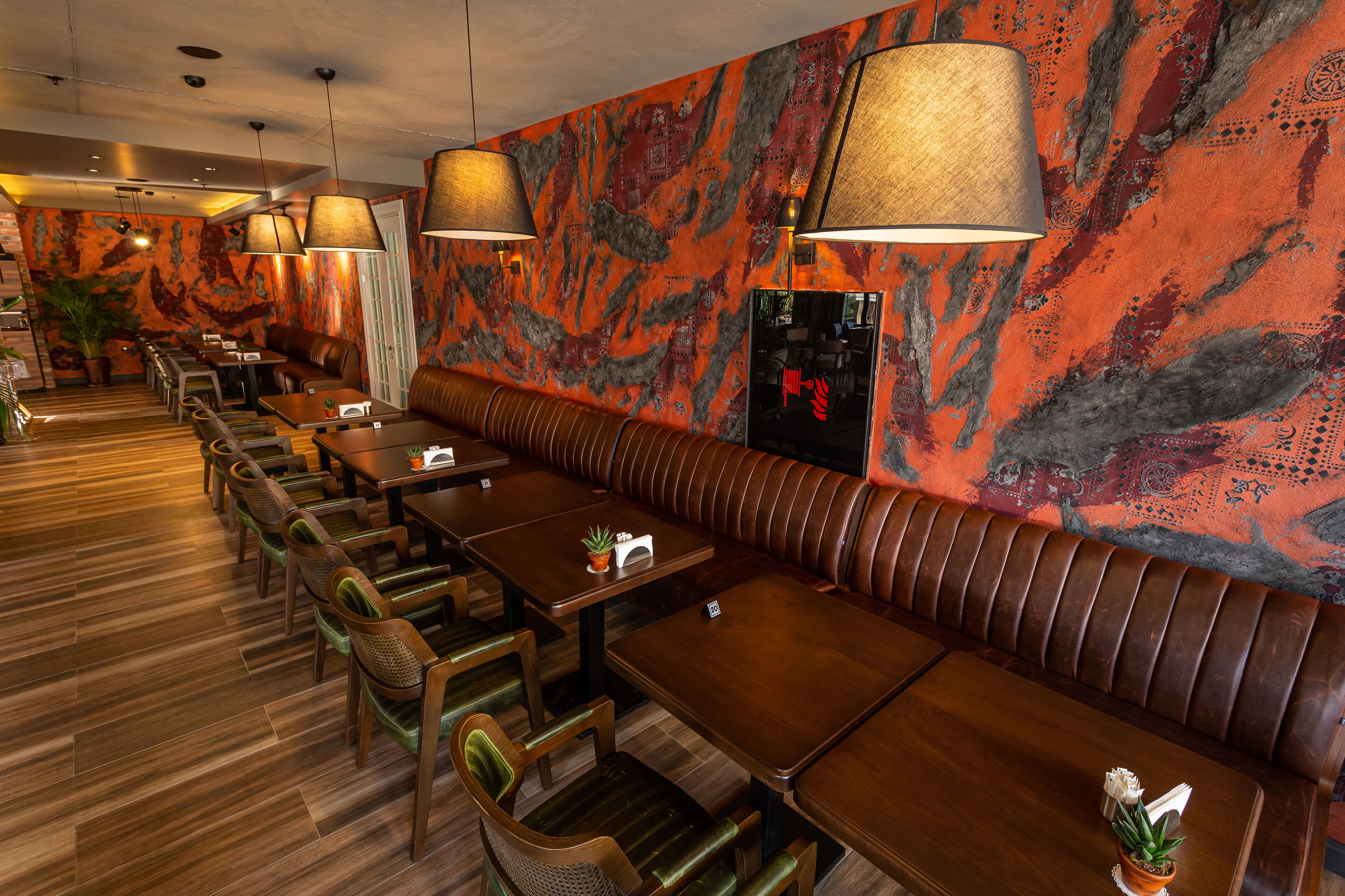 A restaurant with wooden tables and booths, a patterned wall, and hanging lamps.