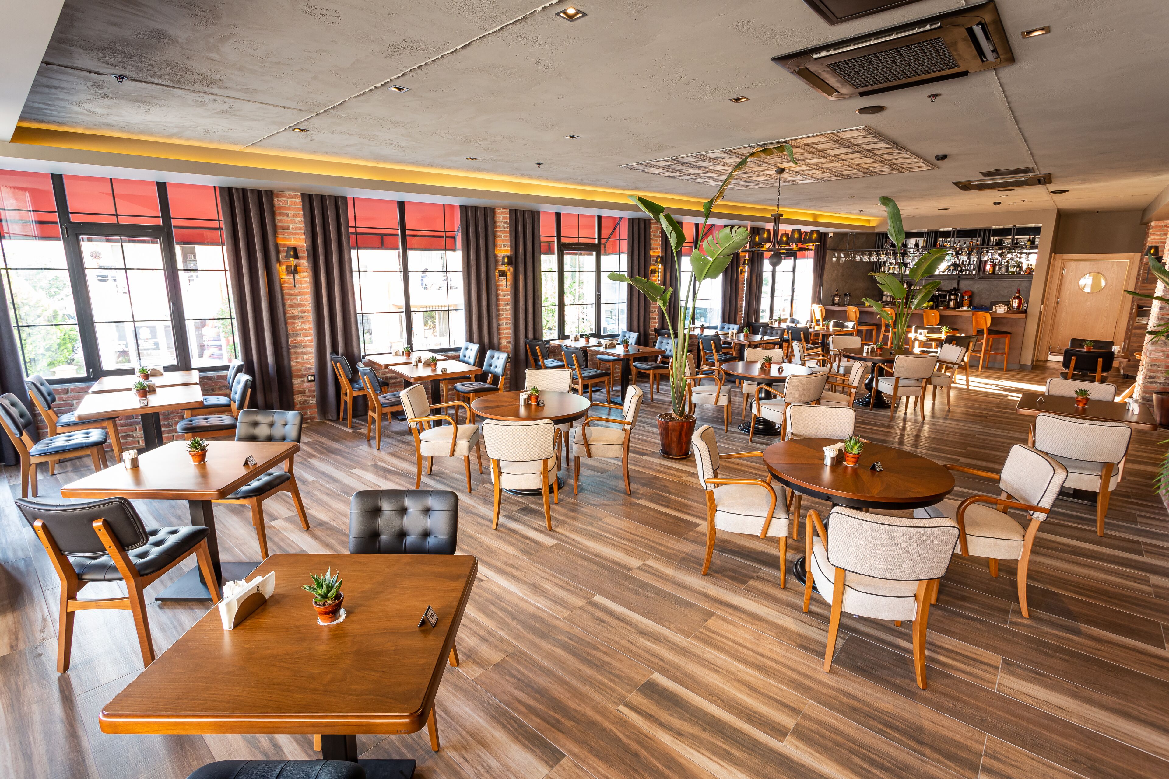 Un restaurante espacioso con varias áreas de estar, incluyendo mesas redondas y cabinas, y una barra al fondo.