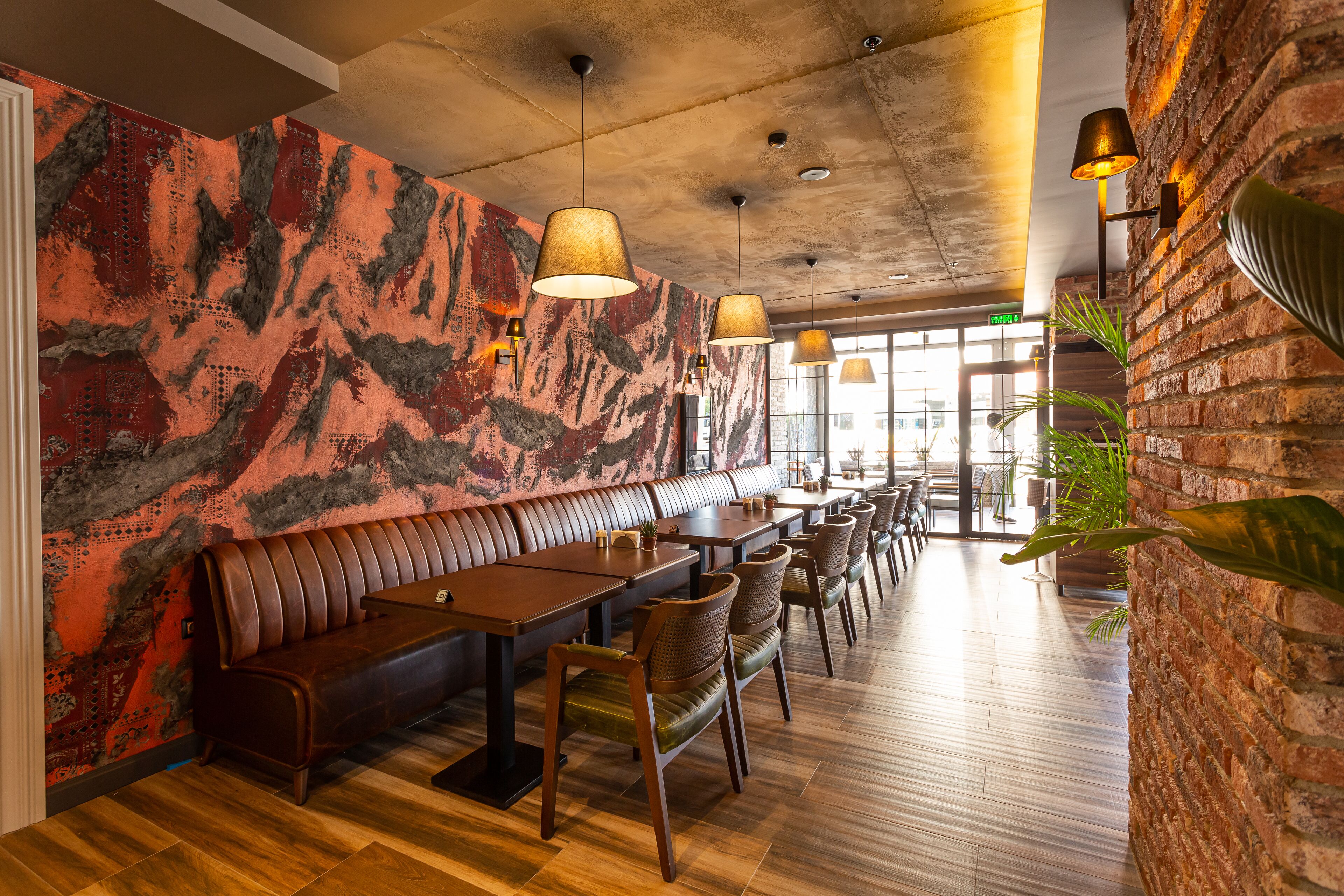 A restaurant interior with a long wooden bench, tables, and chairs.