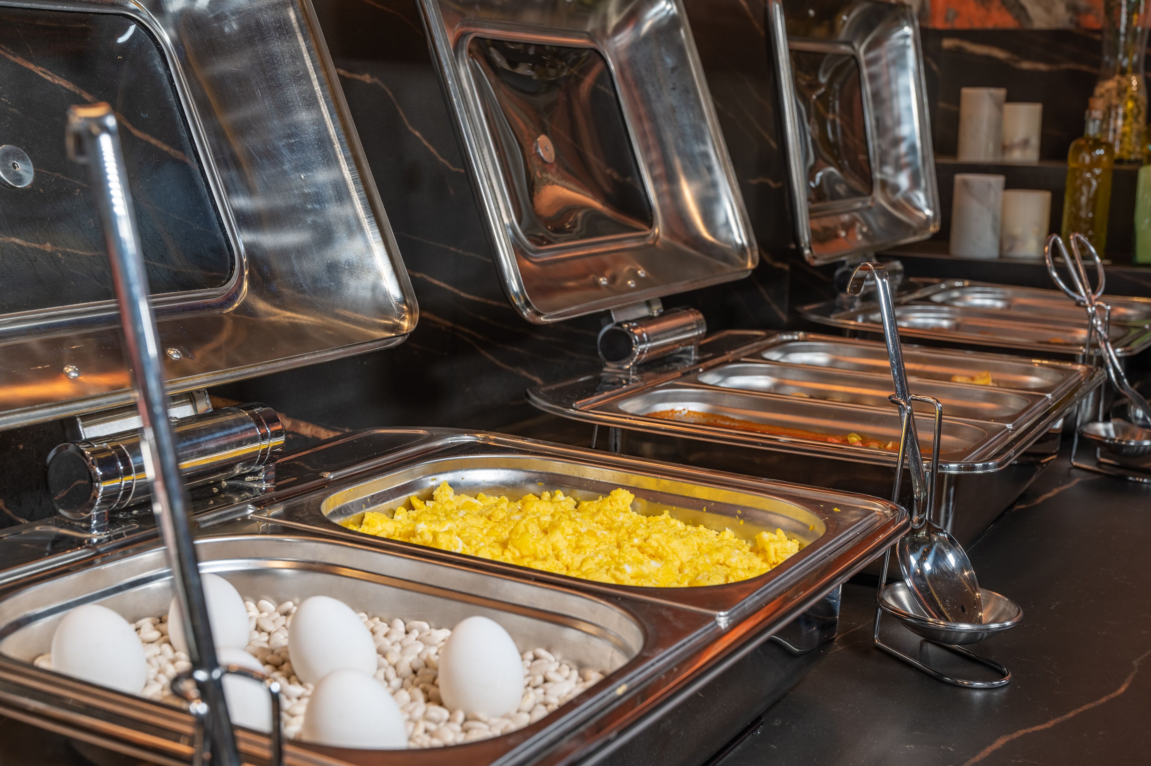 A buffet with various food items including eggs, beans, and scrambled eggs.