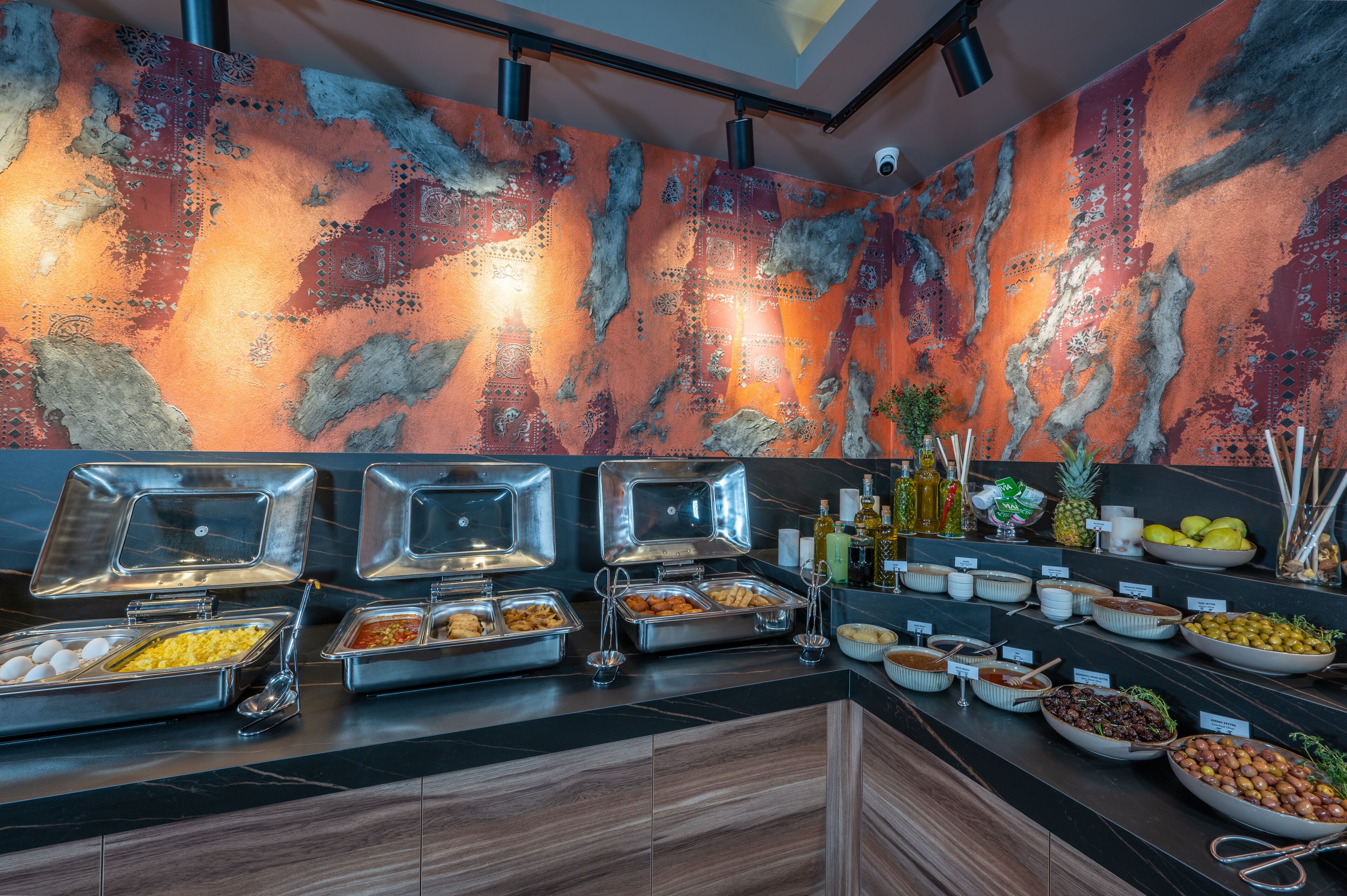 A buffet with various food items and a decorative wall with a unique pattern.