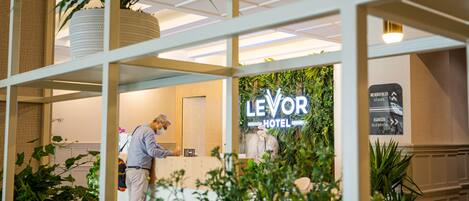 A hotel reception area with a sign for 'LEVOR HOTEL' and directional signs for 'MEROENIER STAIRS' and 'ASANSUUR ELEVATOR'.
