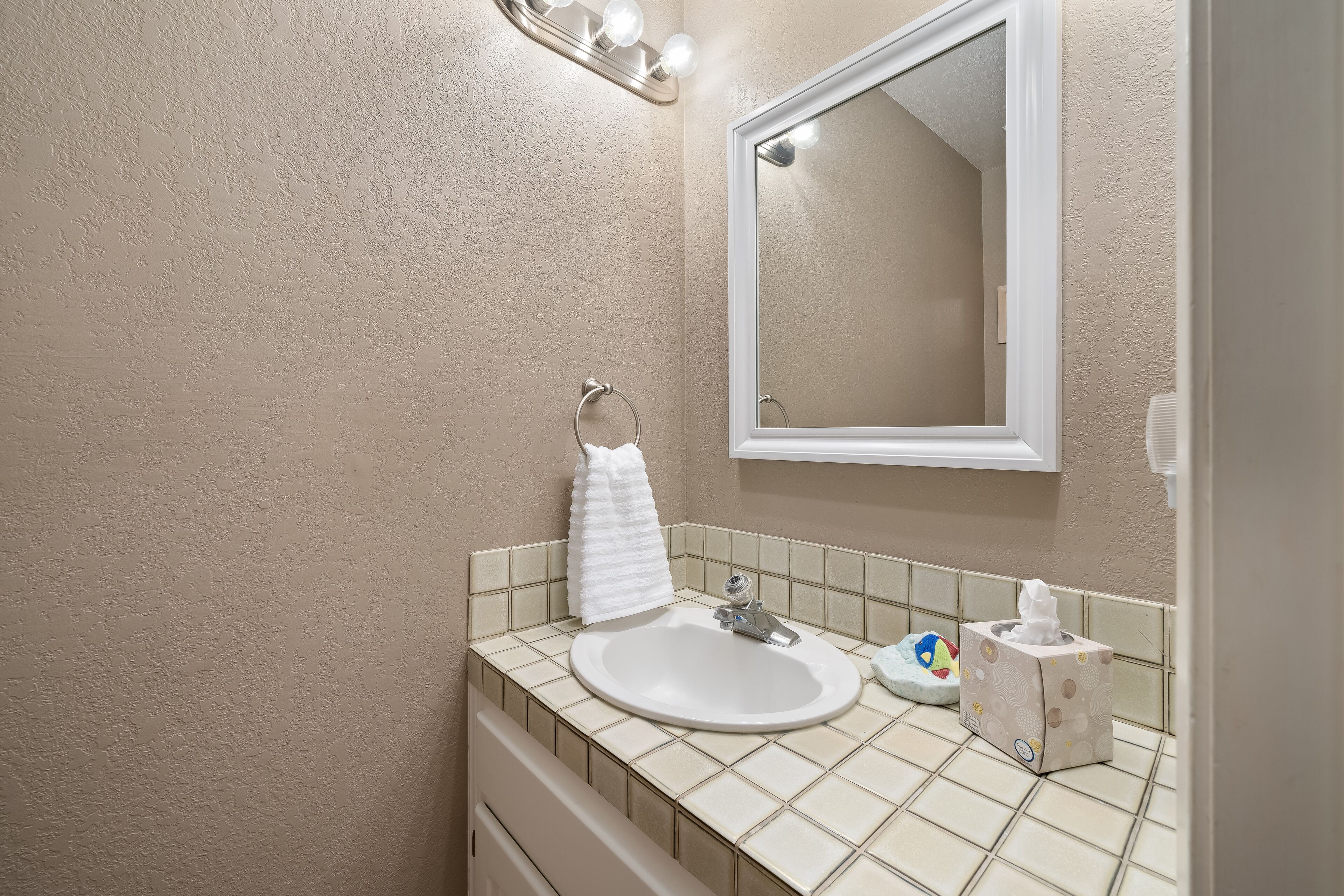 A bathroom with a white sink, a mirror, and a towel rack.