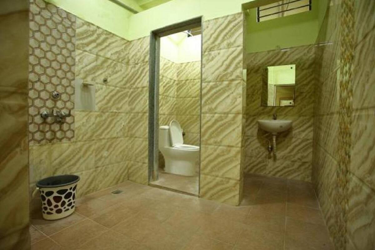 A bathroom with a marble wall, a toilet, a sink, and a trash bin.
