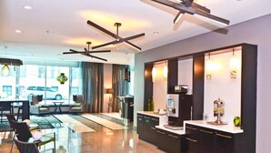 Een moderne hotellobby met een glazen scheidingswand, zithoek en een kitchenette.