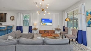 A modern living room with a gray sectional sofa, a wooden coffee table, and a TV mounted on the wall. - Grand, Luxurious Home, Toy Story Room and Big Pool Area #9cg476 (Davenport)