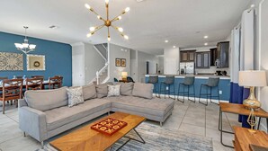 A modern living room with a sectional sofa, a wooden coffee table, and a chandelier. - Grand, Luxurious Home, Toy Story Room and Big Pool Area #9cg476 (Davenport)