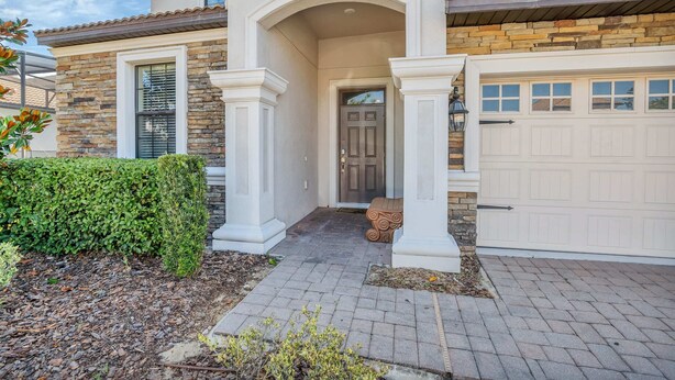 A residential house with a stone facade, a garage, and a well-maintained front yard. - Grand, Luxurious Home, Toy Story Room and Big Pool Area #9cg476 (Davenport)