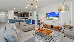 A modern living room with a grey sectional sofa, a wooden coffee table, and a TV mounted on the wall. - Grand, Luxurious Home, Toy Story Room and Big Pool Area #9cg476 (Davenport)