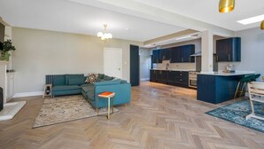 A spacious living area with a sofa, a small table, and a herringbone-patterned floor.