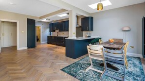 A modern kitchen with dark cabinets, a central island, and a dining area with a table and chairs.