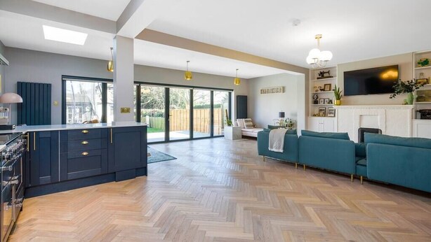 A spacious living area with a kitchen, a sofa set, and a fireplace.